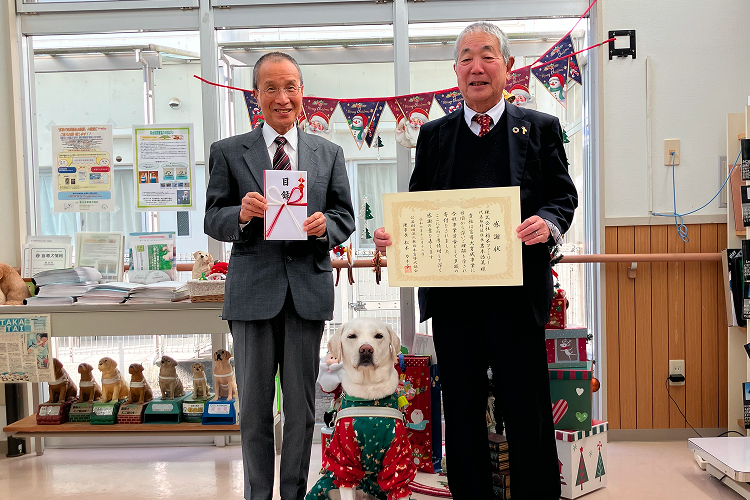 感謝状と目録を持つ2人の男性と盲導犬